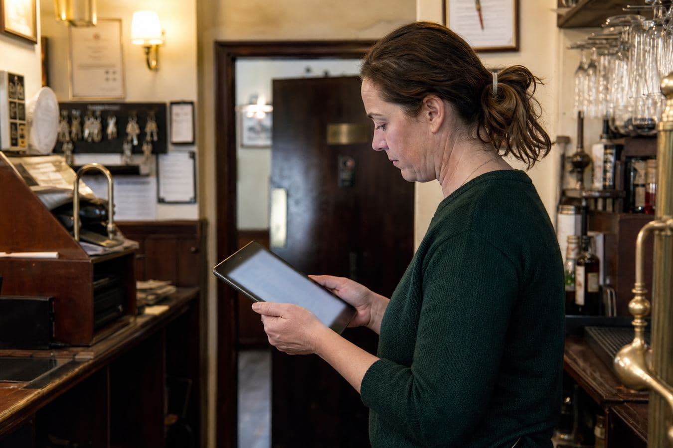 A pub manager checking figures on a tablet.